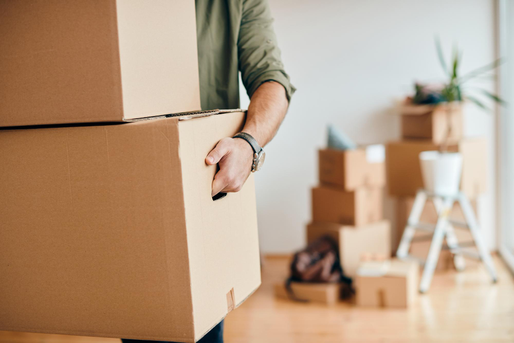 closeup man carrying cardboard boxes while relocating into new apartment